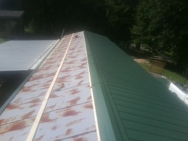 Old rusted panels beside newly installed green metal roofing — Wind Damage Roof Repair by Roofing Brothers in Lucas