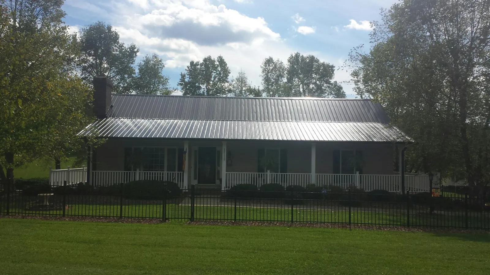 Gray metal roof on a brick ranch with a full width front porch — Gutter Guard Installation work by our crew in Lucas