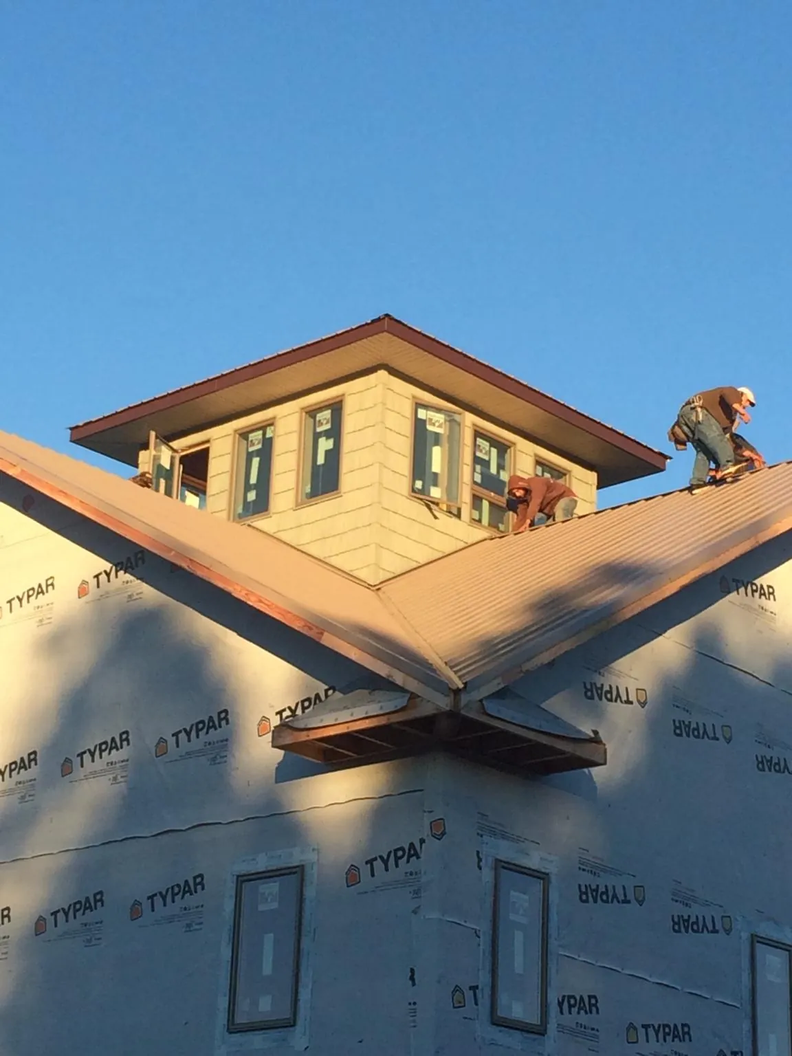 Roofers working around a rooftop cupola on a new metal roof at sunset — Roof Waterproofing in Lucas by Roofing Brothers